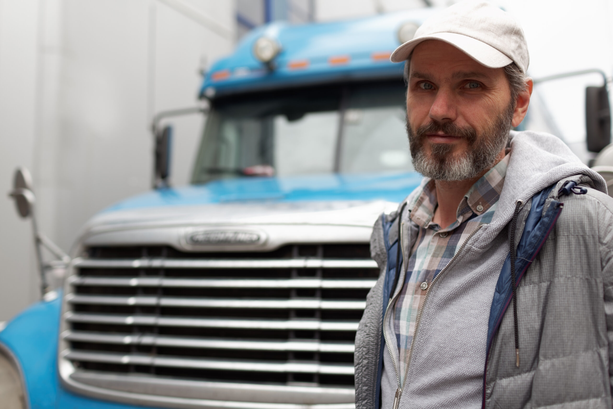 Serious truck driver in front of a blue semi truck